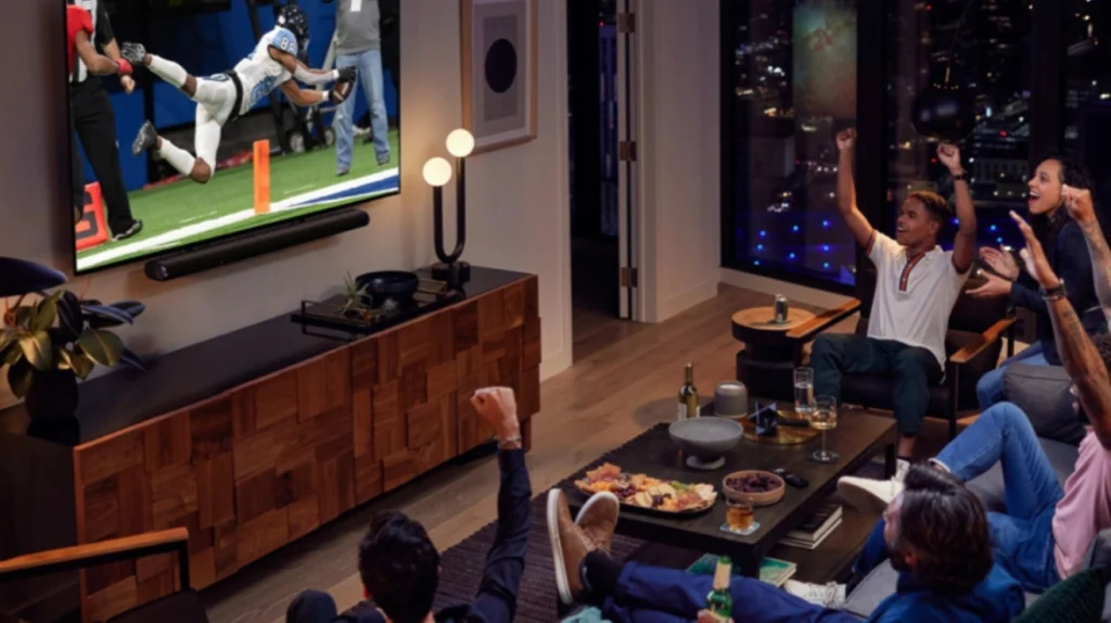 Group of friends cheering while watching a live sports event on IPTV in a modern living room, enjoying the game together.